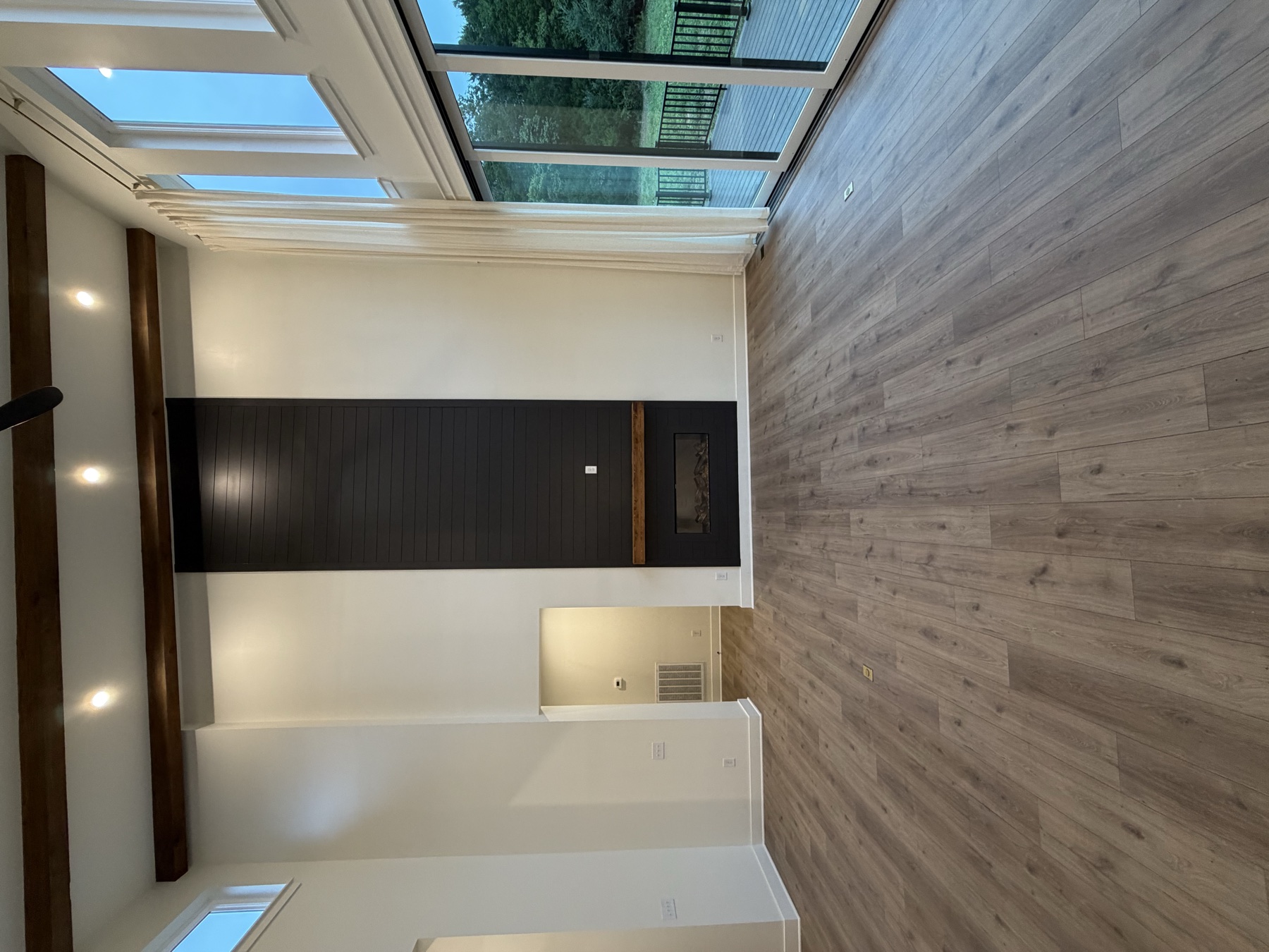Tall living space with a dark fireplace wall and exposed ceiling beams