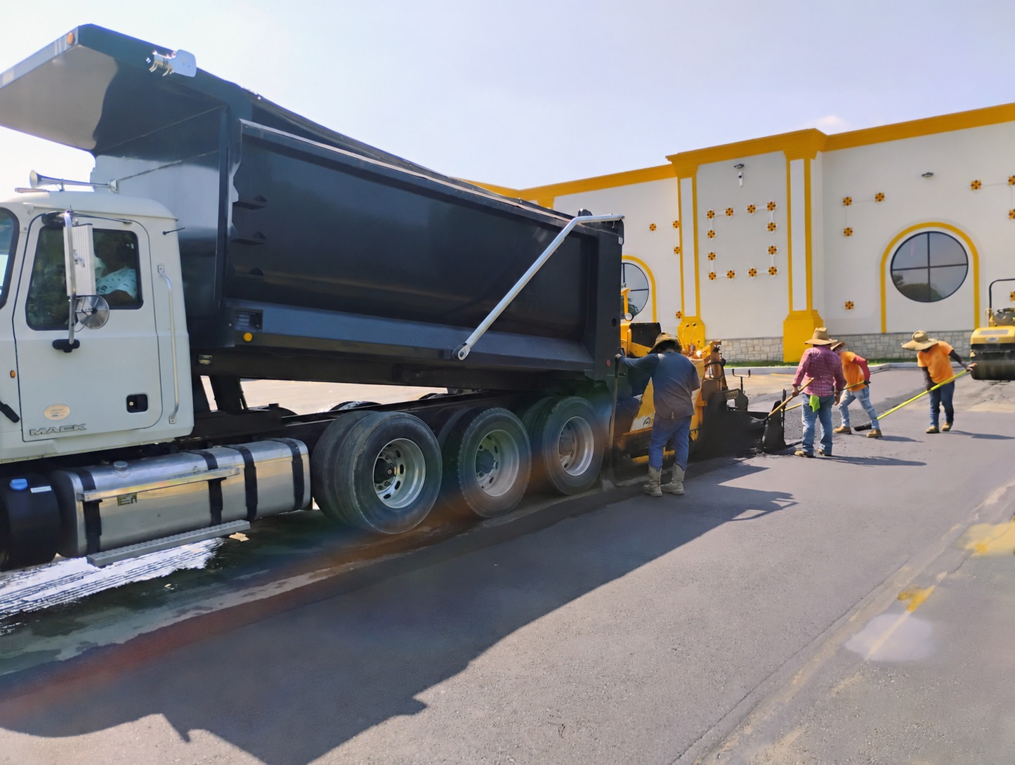 Paving crew placing asphalt from a dump truck