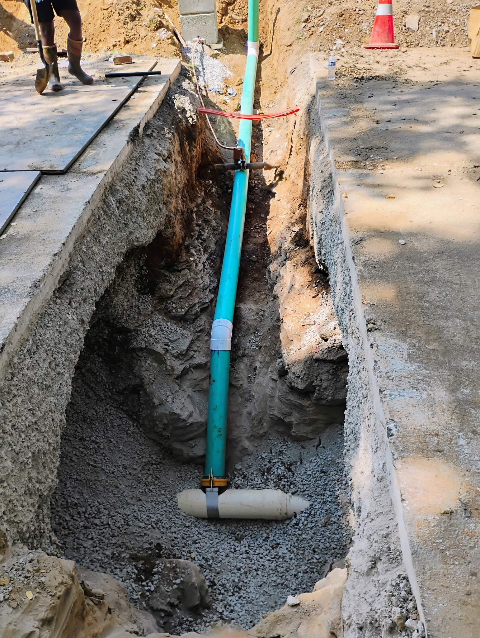 Utility pipe installed through an open trench between concrete slabs